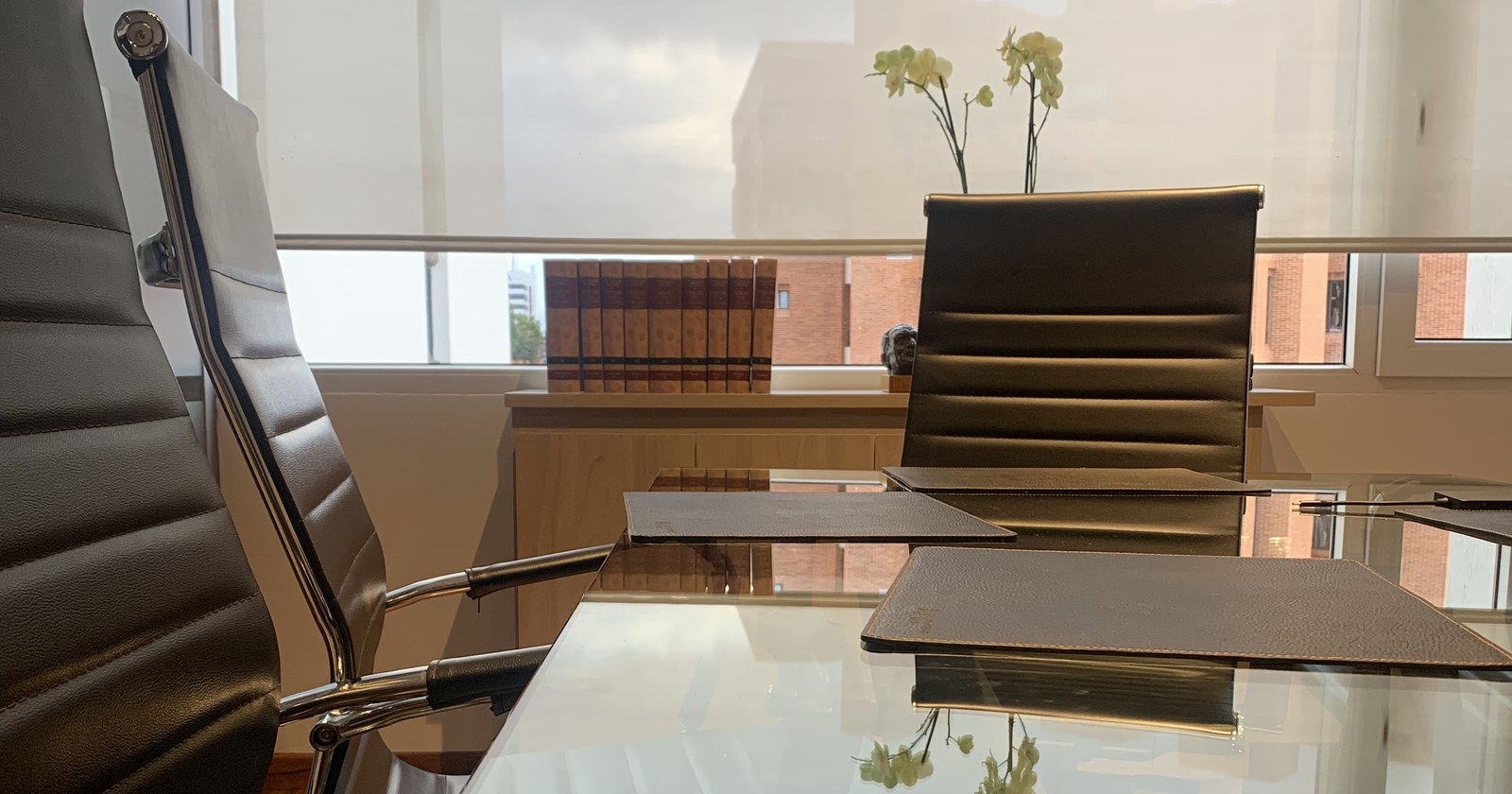 Sala de reuniones de Juan Antonio Matiz, abogado en audiencias preliminares, con mesa de vidrio y biblioteca jurídica al fondo
